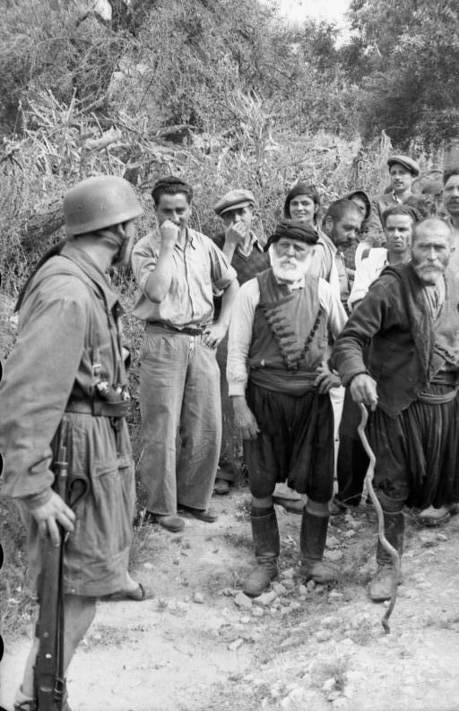 Χωρικοί και ηλικιωμένοι αντιμέτωποι με τους Γερμανούς αλεξιπτωτιστές, λίγο πριν την εκτέλεσή τους στο Κοντομαρί, Κρήτη, 1941 (φωτ. Φραντς Πέτερ Βάιξλερ) │ ΠΗΓΗ : el.wikipedia.org