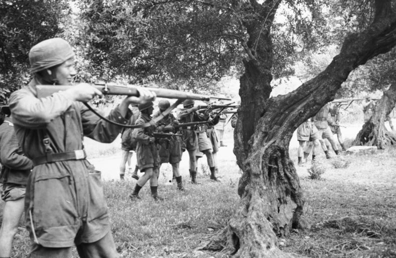 Το εκτελεστικό απόσπασμα σε θέση βολής στους ελαιώνες έξω από το Κοντομαρί. Ο στρατιώτης που μειδιά στο προσκήνιο, εντοπίστηκε μετά από πολλά χρόνια κατά τις διακοπές του στην Κρήτη από ξενοδόχο που τον αναγνώρισε. Όταν του έδειξε τις φωτογραφίες, παραδέχτηκε ότι ήταν αυτός και κυνικά απάντησε ότι εκτελούσε εντολές και έκτοτε δεν εθεάθη ξανά από τον Έλληνα ξενοδόχο στην περιοχή │ ΠΗΓΗ : el.wikipedia.org